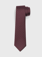 Burgundy tie with small white polka dots, rolled and laid flat.