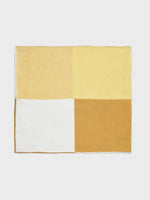 A rectangular fabric with four color blocks: two shades of yellow, white, and brown.