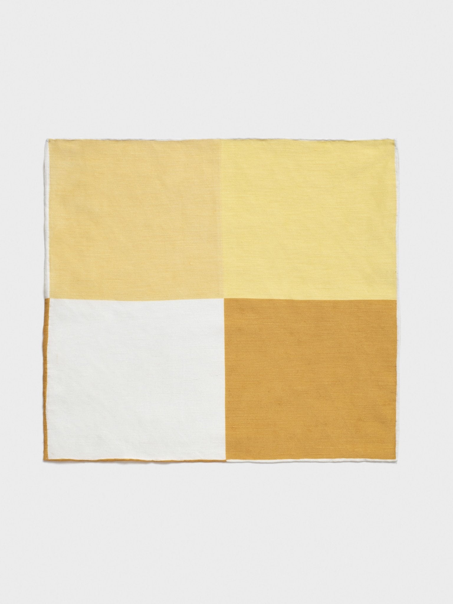 A rectangular fabric with four color blocks: two shades of yellow, white, and brown.